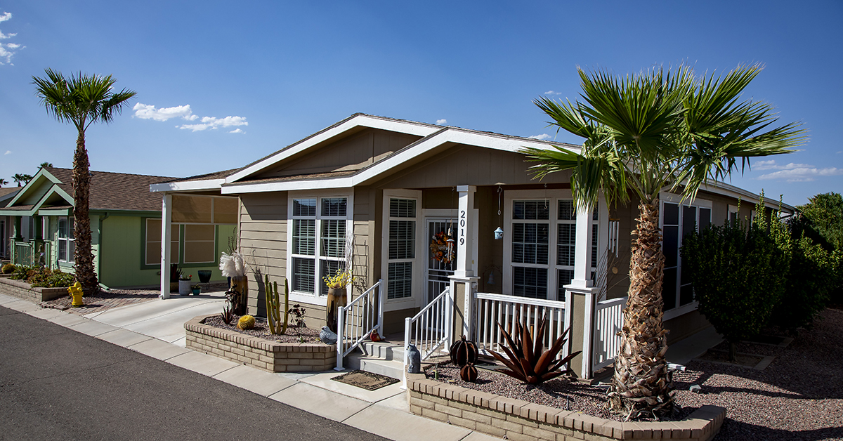 A modern manufactured home community with residents chatting on sidewalk.